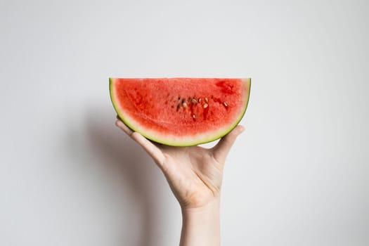 Hand holding a slice of fresh watermelon against white background.