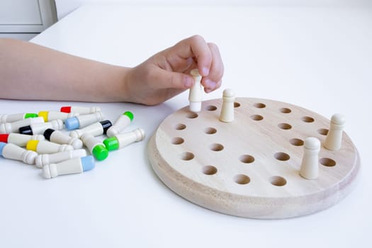 Child hand engaging with wooden peg puzzle for cognitive development.