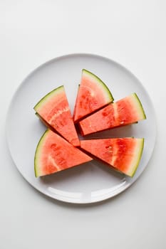 Juicy watermelon slices arranged on white plate.