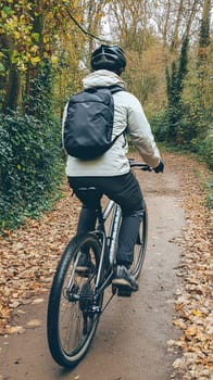 A cyclist with a backpack rides through a leafy forest path, enjoying the autumn scenery.