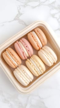 A neat arrangement of assorted macarons in pastel colors placed on a white marble background.