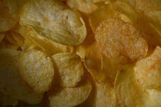 Golden, crispy potato chips piled high invite snack enthusiasts to indulge during a warm evening with friends. The satisfying crunch and salt bring joy to the gathering.