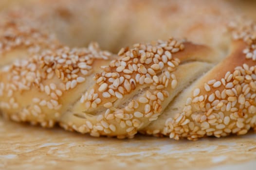 Warm sunlight filters through the kitchen as a beautifully braided loaf, covered in toasted sesame seeds, rests on a wooden surface, inviting taste and comfort.