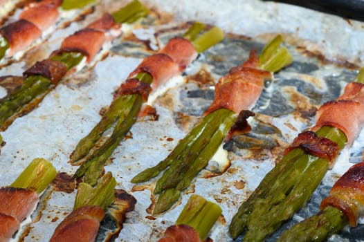 Fresh asparagus spears are beautifully wrapped in crispy bacon, sizzling with flavor on a baking sheet. This barbecue delight is perfect for outdoor gatherings, blending savory and fresh tastes.