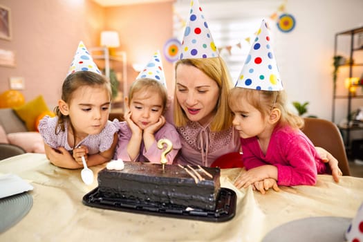 Four joyful children and an adult celebrate a birthday with cake.