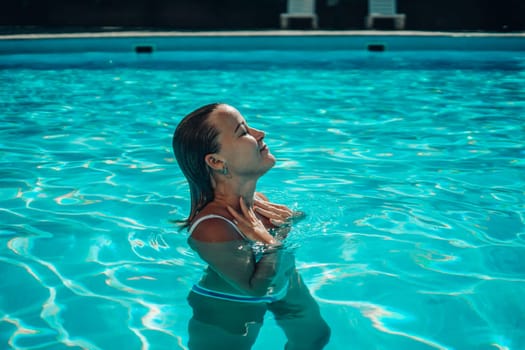 A woman is swimming in a pool. She is smiling and enjoying the water