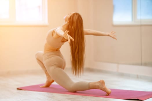 Girl does yoga. Young woman practices asanas on a beige one ton background