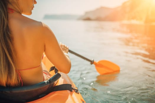Woman in kayak back view. Happy woman with long hair in a swimsuit and hat floating in kayak on the sea. Summer holiday vacation. Summer holidays vacation at sea