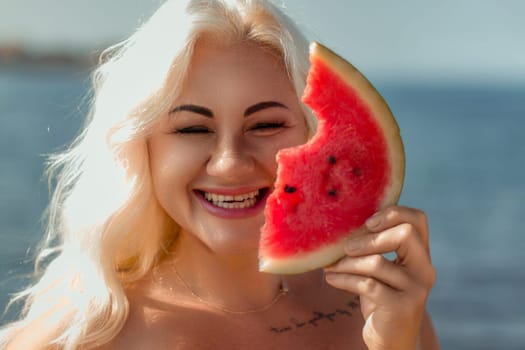 Smiling blonde woman holds a bitten watermelon slice, partially obscuring her face. Beach background visible.