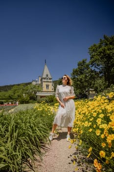 A woman in a white dress is walking through a field of yellow flowers. The scene is peaceful and serene, with the woman enjoying the beauty of nature