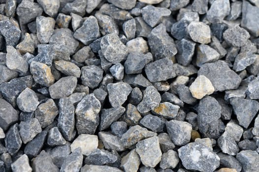 Various sizes and shapes of gravel create intricate patterns on the ground, glinting under the warm afternoon sun. The mixture of gray and cream offers a striking visual contrast.