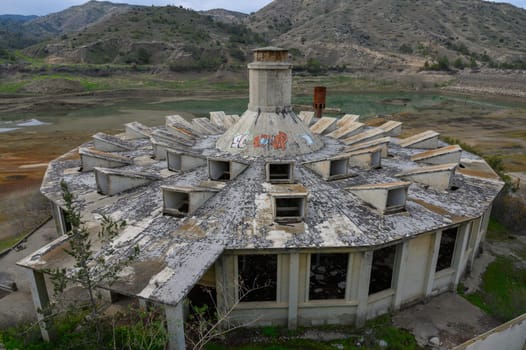 Nestled amidst rolling hills, the dilapidated building stands silently, adorned with graffiti and surrounded by nature's quiet splendor.