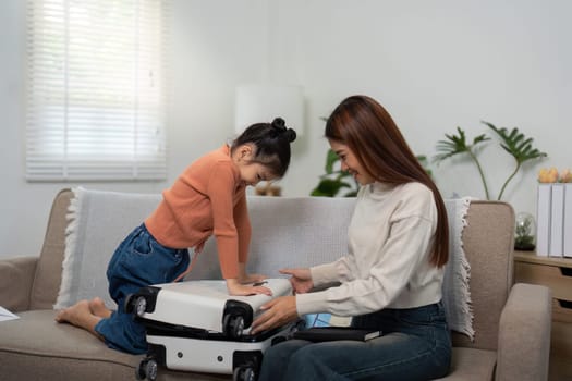 A mother and her daughter prepare their luggage with laughter, showcasing their strong family bond and shared excitement for the upcoming journey.
