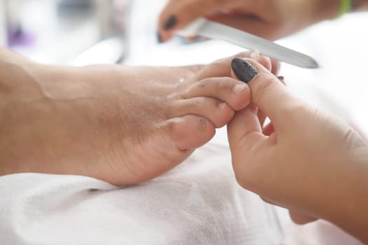 A technician carefully files toenails during a relaxing pedicure service.