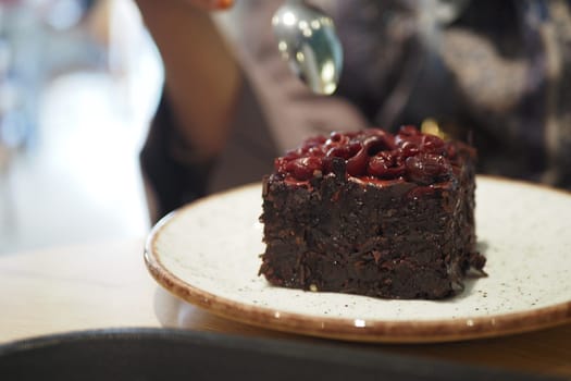 A rich chocolate cake topped with cherries is ready to be enjoyed.