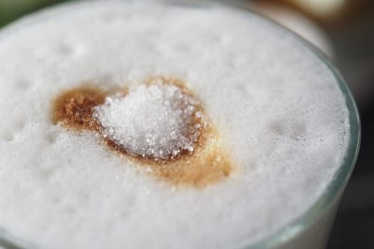 A rich coffee drink features foam and sugar garnishing its surface.