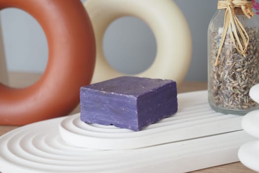 A bar of lavender soap sits amongst modern decor on a wooden table.