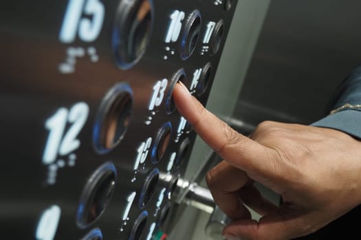 A person selects the thirteenth floor in an elevator setting.