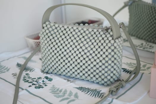 Unique green handbag featuring textured bead design on a table.