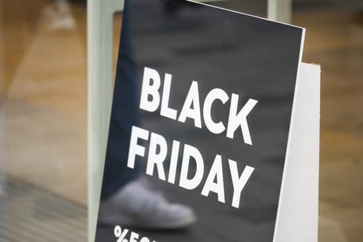 Shopping enthusiasts are drawn to a Black Friday sale sign promoting discounts.