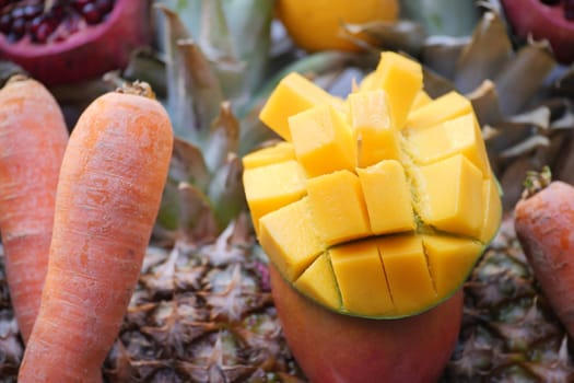 Colorful fruits including mango and carrot present on a market table.