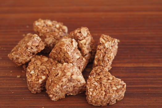 Delicious granola squares are stacked on a smooth wooden surface.