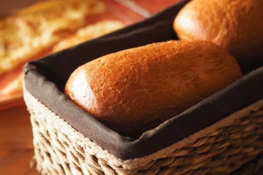 Two golden-brown bread rolls rest in a woven basket, invitingly fresh.