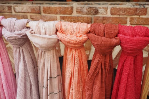 Rows of vibrant scarves display various textures and hues in a market.