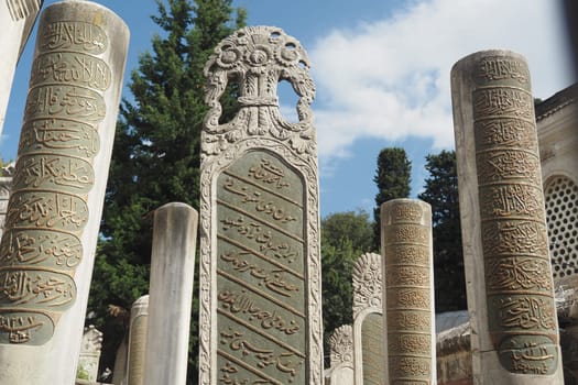 Carved stone markers with inscriptions stand tall amidst lush greenery.