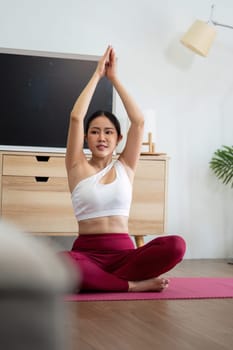 A dedicated yoga practitioner engages in a pose, focusing on breathing and mindfulness in the comfort of her home, embodying wellness and tranquility.