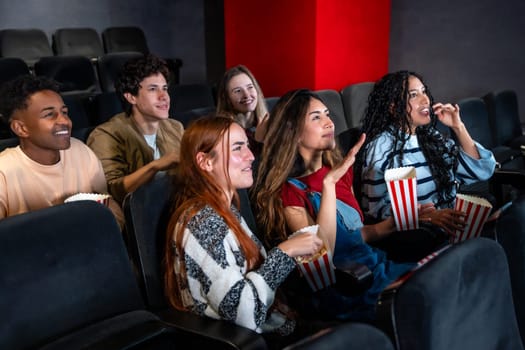 Friends enjoying a film in a movie theater, munching on popcorn and sharing laughter, creating joyful memories together
