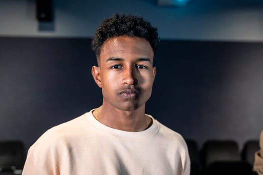 Portrait of a young man standing in a movie theater during a movie session, possibly participating in a movie disco dance or a special event