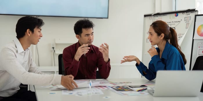 In a lively brainstorming session, three UX UI designers exchange ideas and feedback, focusing on enhancing user experience through collaborative dialogue.