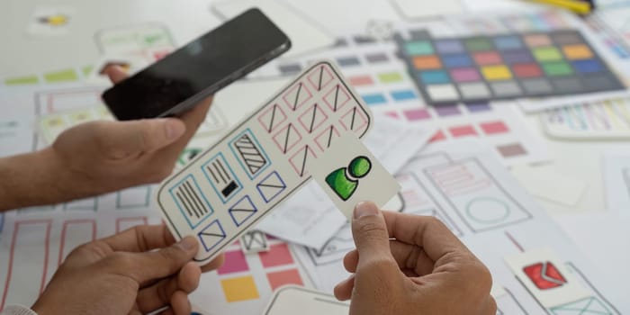 A team is engaged in a creative session, discussing mobile app designs and wireframes while using sketches to visualize ideas and collaborate effectively.