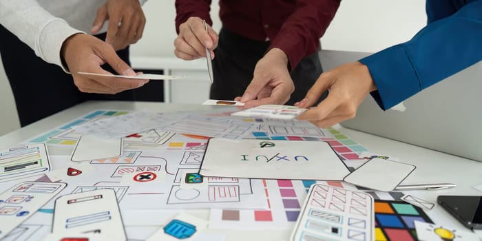 A diverse team is engaged in a brainstorming session, exchanging ideas and reviewing design drafts for a user-friendly interface, ensuring all views are captured.