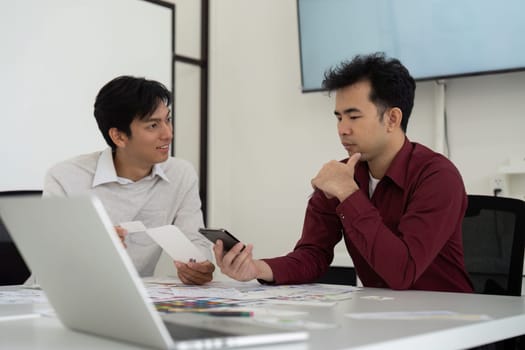 In a collaborative environment, two professionals discuss and analyze a mobile application's interface, exchanging ideas and feedback.
