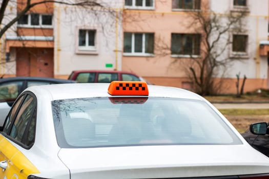 A white taxi that features an orange sign mounted prominently on its roof, indicating its availability for passengers to hail