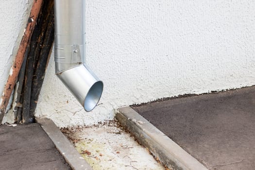 A sturdy metal pipe is currently hanging off the edge of a tall building, potentially serving various functions like plumbing and drainage