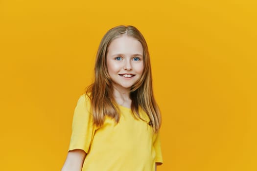 Bright and joyful young girl in a yellow shirt, exuding happiness and positivity in front of a warm yellow background, ideal for seasonal and motivational content