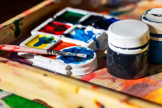 A colorful tray filled with watercolors accompanied by a brush neatly placed on a table, inviting creativity and artistic expression