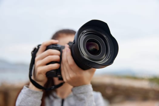 A dedicated young female photographer holds a DSLR camera, ready to capture stunning outdoor scenes, reflecting her love for photography and nature in a peaceful environment