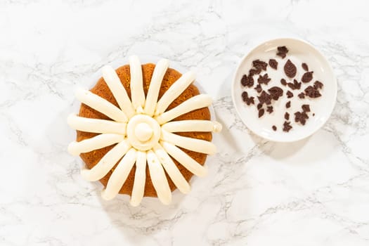 Flat lay. Icing the pumpkin bundt cake with cream cheese frosting and decorating it with chocolate leaves.