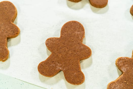 Close-up view of a single gingerbread man cookie on parchment paper, highlighting its festive design and baked finish.