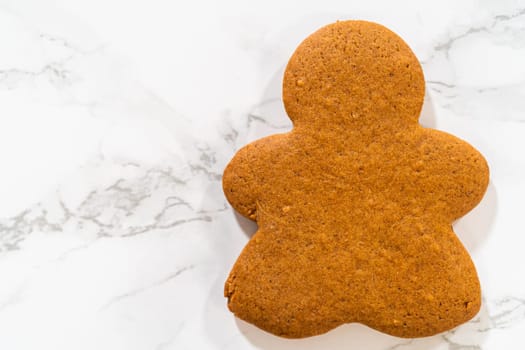 A single Orange Zest Gingerbread Cookie in gingerbread girl shape placed on a white marble background, highlighting its rich color and smooth finish.