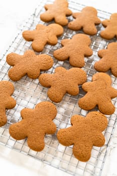 Close-up view of a tray of freshly baked gingerbread man cookies placed on a cooling rack, highlighting festive details.