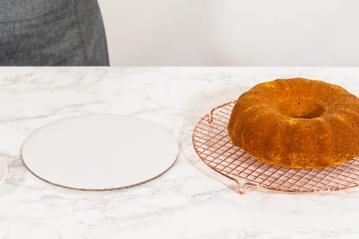 Icing the pumpkin bundt cake with cream cheese frosting and decorating it with chocolate leaves.
