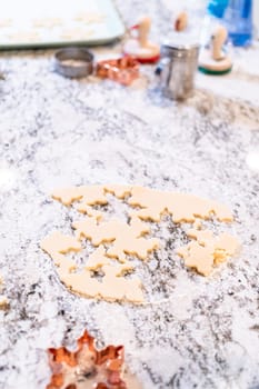 Enjoy the festive tradition of rolling out cookie dough and cutting snowflake-shaped sugar cookies, perfect for the holiday season.