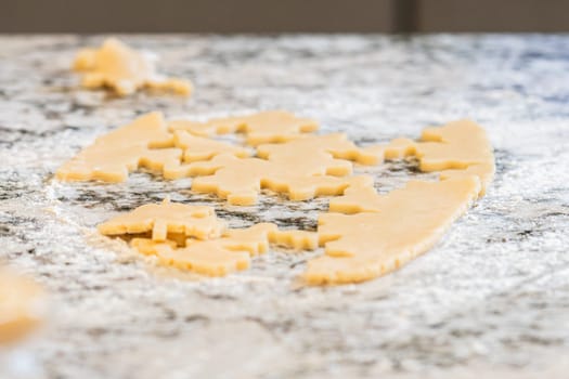 Enjoy the festive tradition of rolling out cookie dough and cutting snowflake-shaped sugar cookies, perfect for the holiday season.