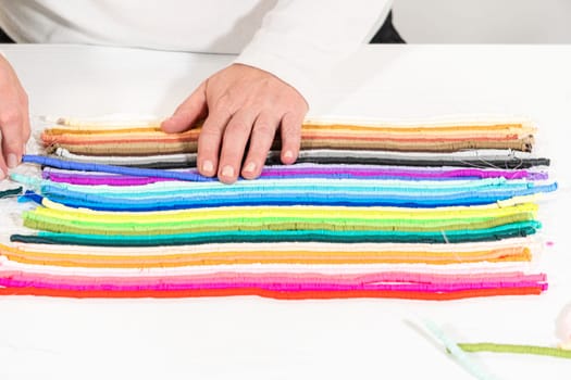 A vibrant collection of clay beads, neatly arranged by color on a white table, ready to inspire young crafters to create their own unique bracelets.