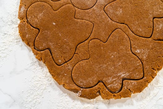 The entire dough sheet is filled with gingerbread girl shapes, ready to be transferred to the baking tray. Captured from a top-down perspective.